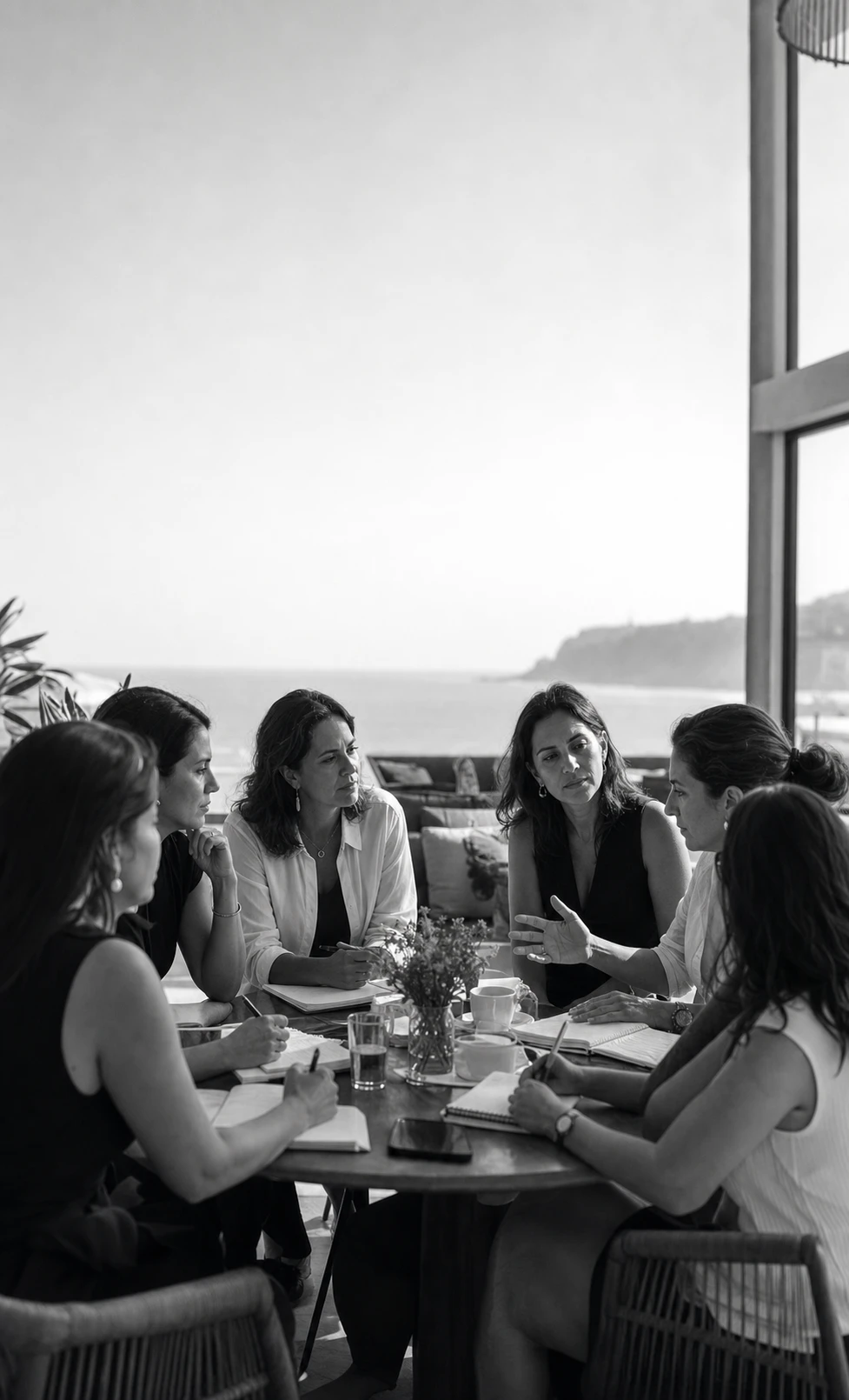 Mujeres conversando alrededor de una mesa de trabajo frente al mar