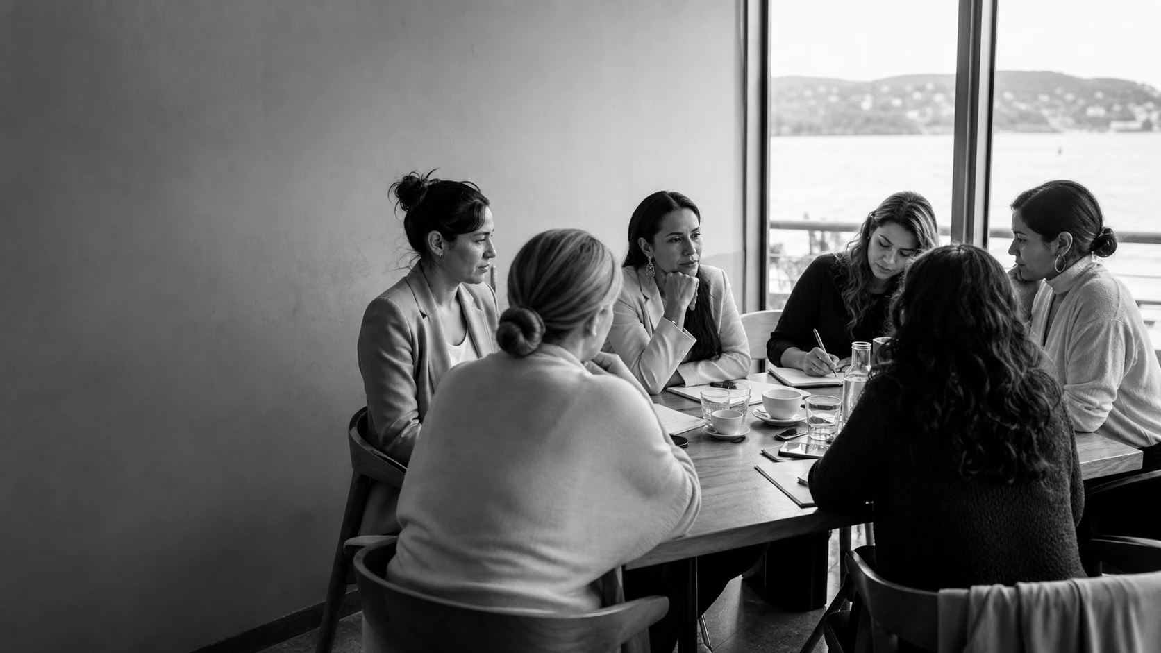 Mujeres de negocios reunidas alrededor de una mesa de trabajo, conversando